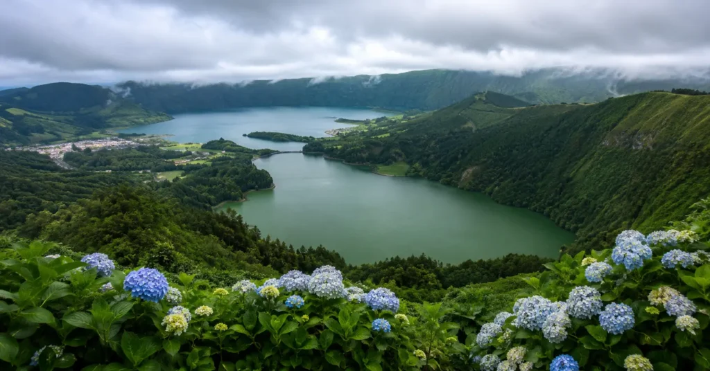 Panoramic view of the green and blue volcanic crater lakes of Sete Cidades in São Miguel, Azores under an overcast sky.
