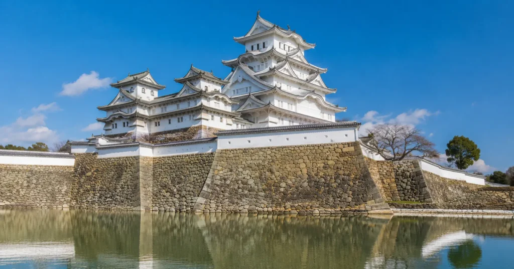 White tiered structure of Himeji Castle rising behind stone defensive walls