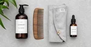 Minimalist layout of a wooden comb, shampoo bottle, and microfiber towel for a hair care routine