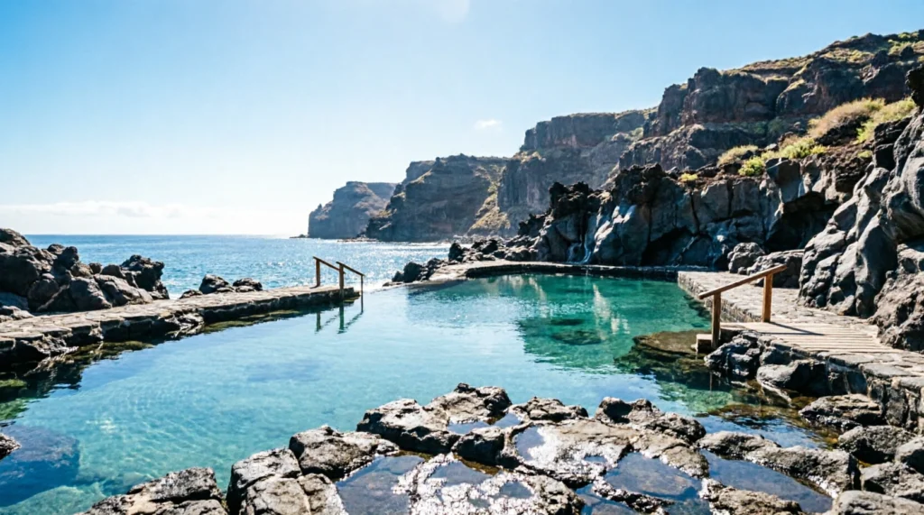 Natural volcanic saltwater pools on the coast of Agaete Gran Canaria under clear blue skies.