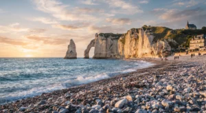 Dramatic chalk cliffs and natural arch over the stone pebble shore of Étretat beach in Normandy, France