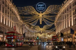Glowing angel Christmas lights suspended over Regent Street in London with red double-decker buses driving below at dusk.