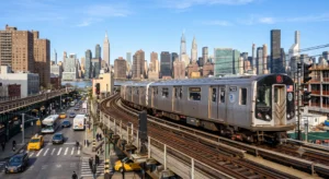 Subway train on elevated tracks in Long Island City Queens with Manhattan skyscrapers in the background.