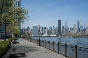 Manhattan skyline viewed across the East River from a quiet walkway in Long Island City, illustrating a smart budget base.